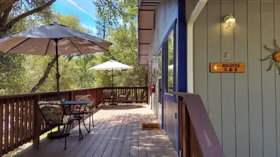 a porch with a table and an umbrella on a house at Little Valley Inn in Mariposa