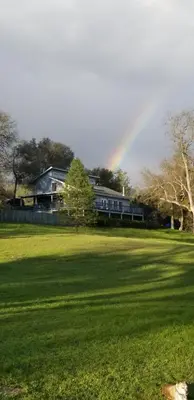 a rainbow in front of a house with a field at Charming Downstairs Unit in Oakhurst