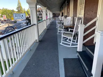 a porch with chairs and a table on a building at Gunn House Hotel in Sonora