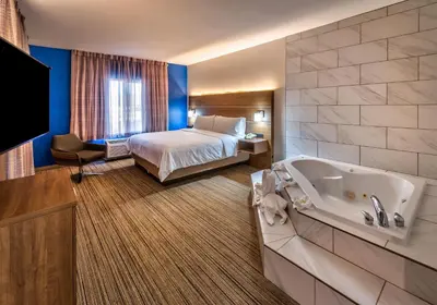 a hotel room with a bed and a tub at Holiday Inn Express Reno Airport by IHG in Reno