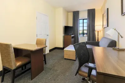 a hotel room with a desk and a bedroom at Staybridge Suites Reno Nevada by IHG in Reno