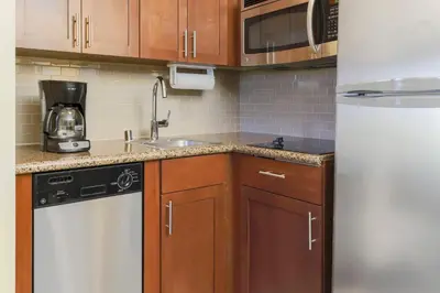 a kitchen with wooden cabinets and a white refrigerator at Staybridge Suites Reno Nevada by IHG in Reno
