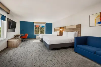 a hotel room with two beds and a blue couch at Holiday Inn Express Fresno River Park Highway 41 by IHG in Fresno