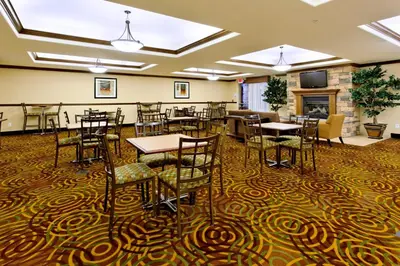 a dining room with tables and chairs and a fireplace at Holiday Inn Express Fresno Northwest - Herndon by IHG in Herndon