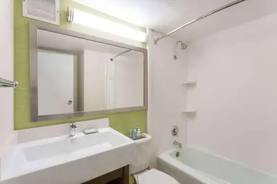 a white bathroom with a sink and a mirror at Wyndham Garden Fresno Yosemite Airport in Fresno