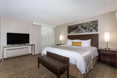 a hotel room with a bed and a flat screen tv at Wyndham Garden Fresno Yosemite Airport in Fresno