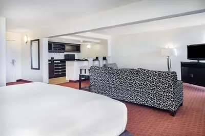 a hotel room with a white bed and a couch at Wyndham Sacramento in Sacramento