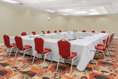 a large conference room with a long table and red chairs at Wyndham Sacramento in Sacramento