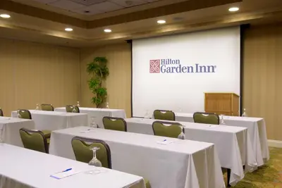 a conference room with white tables and chairs and a screen at Hilton Garden Inn Sacramento Elk Grove in Elk Grove