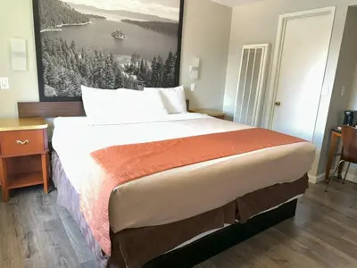 a bedroom with a large bed with a painting on the wall at Alpine Inn & Spa in South Lake Tahoe