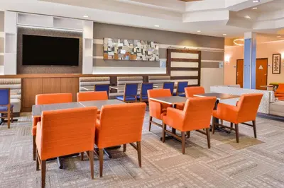 a dining room with tables and chairs and a flat screen tv at HOLIDAY INN EXPRESS & SUITES ELK GROVE CENTRAL - HWY 99 by IHG in Elk Grove