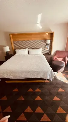a bedroom with a large bed and a chair at Holiday Inn Rancho Cordova - Northeast Sacramento by IHG in Rancho Cordova