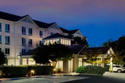 a building with a car parked in a parking lot at Hilton Garden Inn Folsom in Folsom