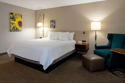 a hotel room with a large bed and a chair at Hilton Garden Inn Folsom in Folsom