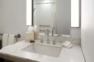 a white bathroom with a sink and a mirror at Hilton Garden Inn Folsom in Folsom