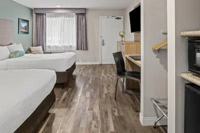 a hotel room with two beds and a desk and a kitchen at Yosemite Westgate Lodge in Groveland