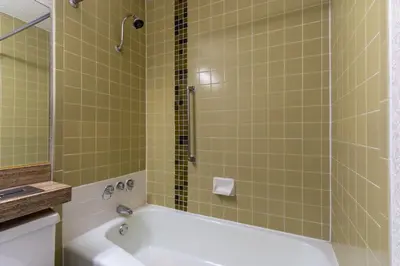a bathroom with a tub and a shower with green tiles at Ramada by Wyndham Reno Hotel & Casino in Reno