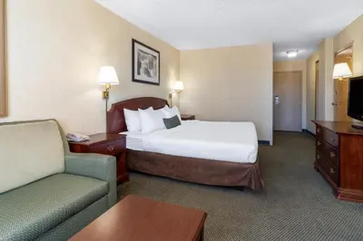 a hotel room with a bed and a couch and a chair at Ramada by Wyndham Reno Hotel & Casino in Reno