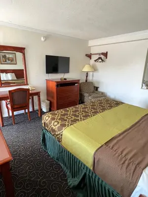 a hotel room with a bed and a desk at Americas Best Value Inn Hanford in Hanford