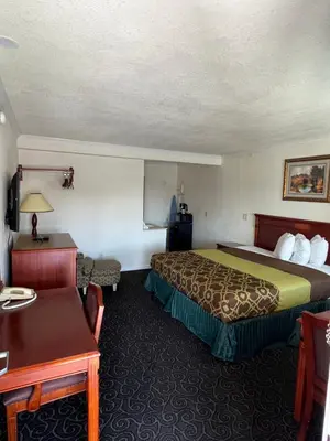 a hotel room with a bed and a table at Americas Best Value Inn Hanford in Hanford