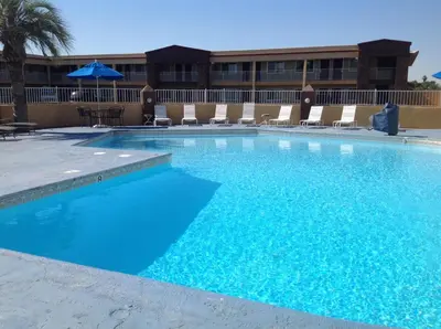 a large blue swimming pool with chairs and an umbrella at Americas Best Value Inn Hanford in Hanford