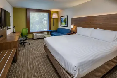 a hotel room with a large bed and a couch at Holiday Inn Express Hotel & Suites Modesto-Salida by IHG in Modesto