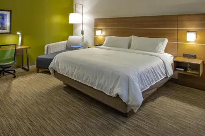 a hotel room with a large bed and a chair at Holiday Inn Express Hotel & Suites Roseville - Galleria Area by IHG in Roseville
