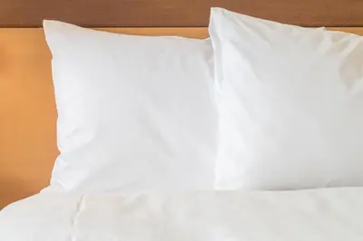 a bed with white sheets and pillows on it at Holiday Inn Express Hotel & Suites Minden by IHG in Minden