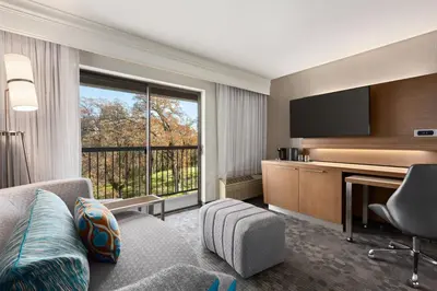 a hotel room with a couch and a desk with a television at Courtyard by Marriott Roseville in Roseville