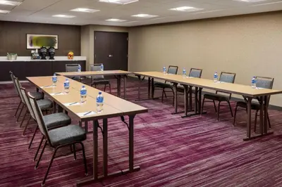 a conference room with tables and chairs and a screen at Courtyard by Marriott Roseville in Roseville