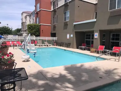 a large swimming pool with chairs and a building at Holiday Inn Express & Suites Tracy by IHG in Tracy