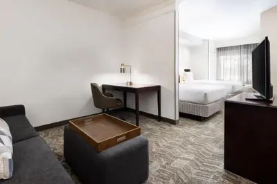 a hotel room with a couch and a desk and a bed at SpringHill Suites Fresno in Fresno