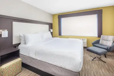 a bedroom with a large bed and a chair at Holiday Inn Express Hotel & Suites Bishop by IHG in Bishop