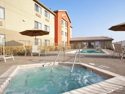 a swimming pool with an umbrella and a building at Holiday Inn Express Westley by IHG in Westley