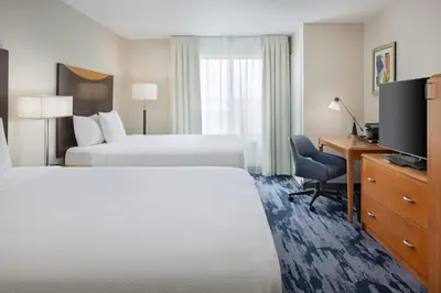 a hotel room with two beds and a desk and a television at Fairfield Inn and Suites Turlock in Turlock