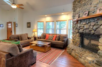 a living room with couches and a large stone fireplace at Alder Lodge in Yosemite West