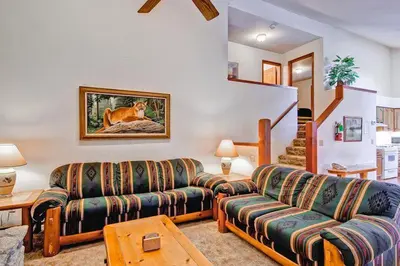 a living room with a couch and a dog painting on the wall at Little Sport in Yosemite West