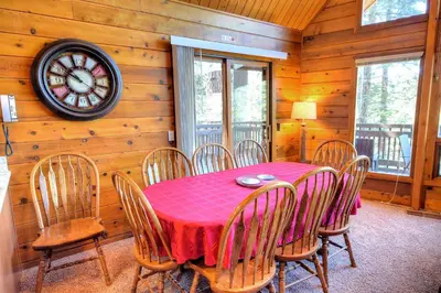 a dining room with a table and chairs and a clock at Treetops Cabin in Yosemite West