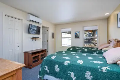 a bedroom with a bed and a desk and windows at Falcons Nest (Downstairs) in Yosemite West