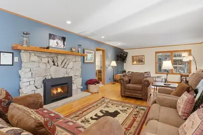 a living room with a stone fireplace at Apple Tree Bear House in Yosemite West