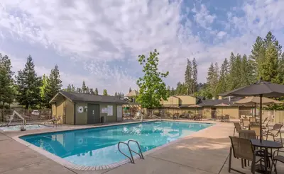 a swimming pool with chairs and an umbrella at WorldMark Bass Lake in Bass Lake