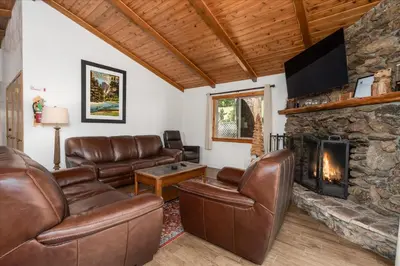 a living room with leather furniture and a stone fireplace at Evergreen in Wawona