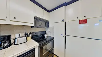 a kitchen with white cabinets and a refrigerator at Great Condo With Free Shuttle to the Village! in Mammoth Lakes