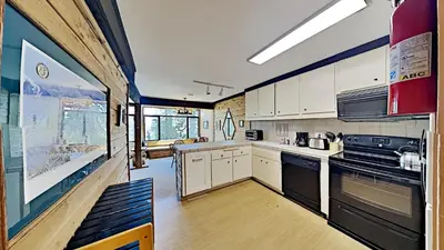 a large kitchen with white cabinets and black appliances at Great Condo With Free Shuttle to the Village! in Mammoth Lakes