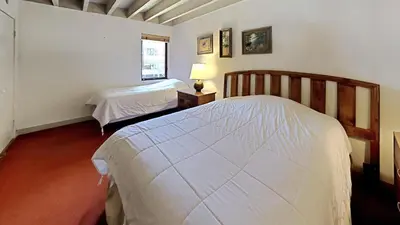 a white bedroom with two beds and a window at Comfortable 4 Bedroom Condo in Mammoth Lakes