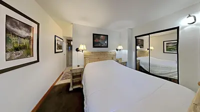 a hotel room with a large white bed and a mirror at Renovated 2 Bedroom Condo with Elevator Access! in Mammoth Lakes