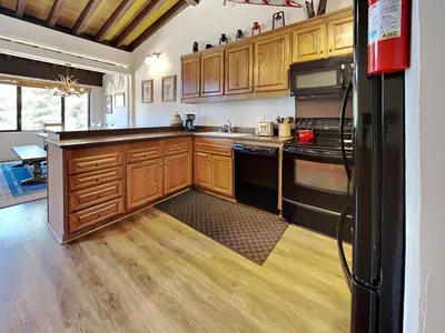 a kitchen with wooden cabinets and black appliances at Remodeled Spacious Cozy Condo Great For Families! in Mammoth Lakes