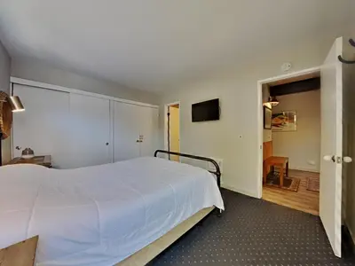 a bedroom with a large white bed and a hallway at Remodeled Spacious Cozy Condo Great For Families! in Mammoth Lakes