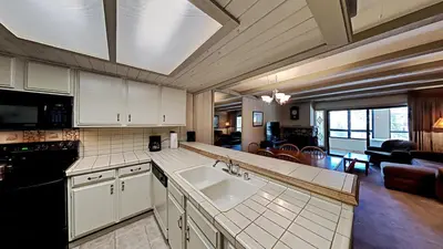 a kitchen with a sink and a living room at Beautiful 2 BR Condo with Mountain View! in Mammoth Lakes