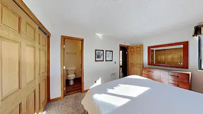 a bedroom with a white bed and a toilet at Nicely Remodeled 2 Bedroom Condo in Mammoth! in Mammoth Lakes